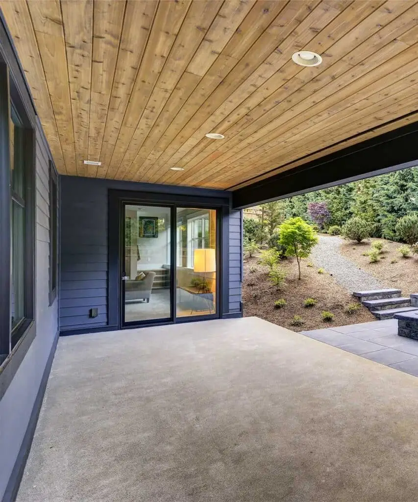 Covered patio with a tongue-and-groove wood ceiling and sliding doors onto a Colorado back garden