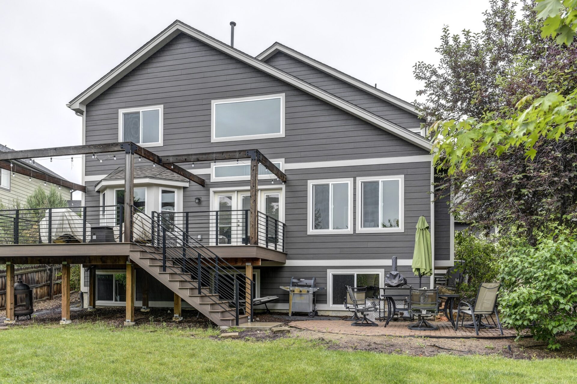Backyard view of a Longmont home with James Hardie lap siding in Iron Gray and Arctic White trim, plus deck and patio.