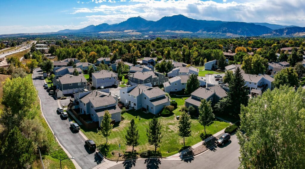 Aerial view of a Boulder, Colorado HOA community after a siding replacement across multiple attached-home buildings by Northern Lights Exteriors, with the Boulder mountains behind