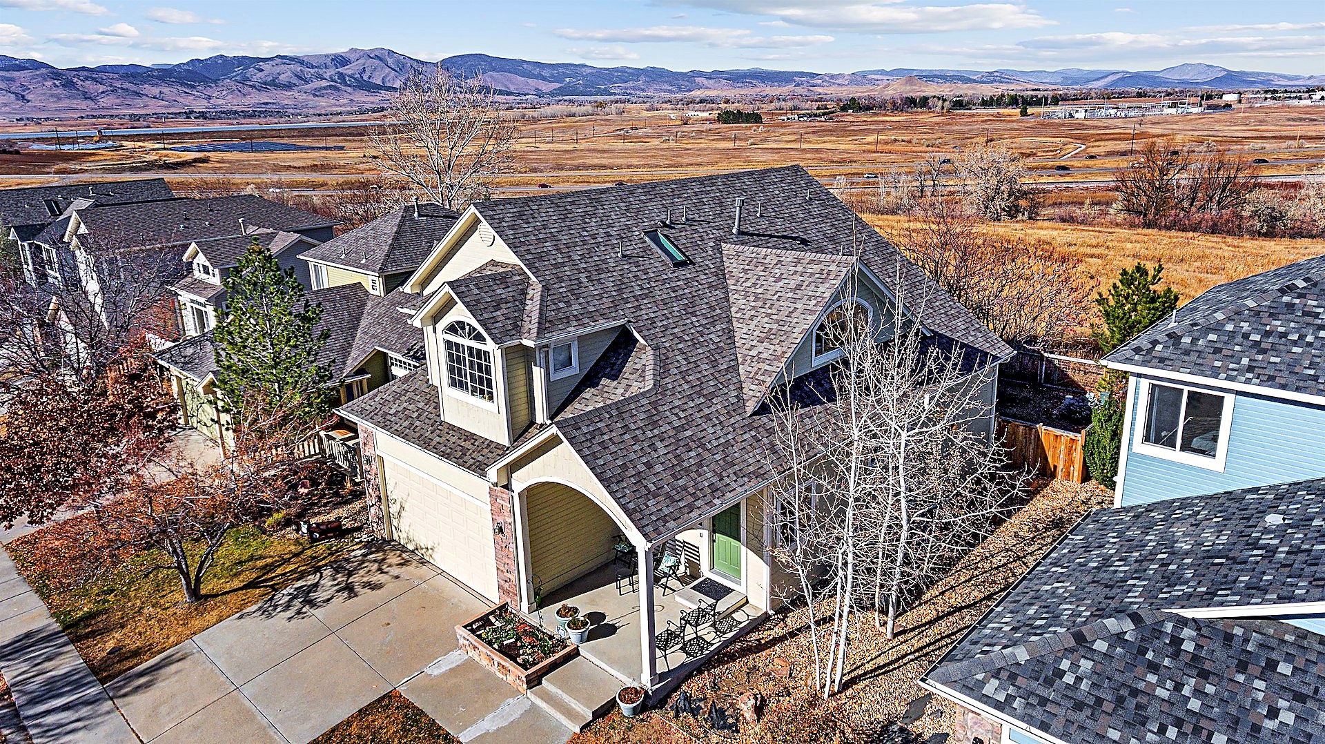 Aerial view of a completed architectural asphalt shingle roof replacement on a home in the Gunbarrel area of Boulder, Colorado, with the Front Range foothills and open space behind