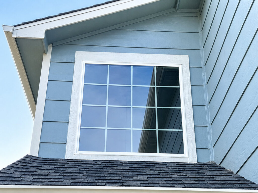 Close-up of a completed replacement window installation in Frederick, Colorado &mdash; white exterior trim integrated into the siding above a roofline.