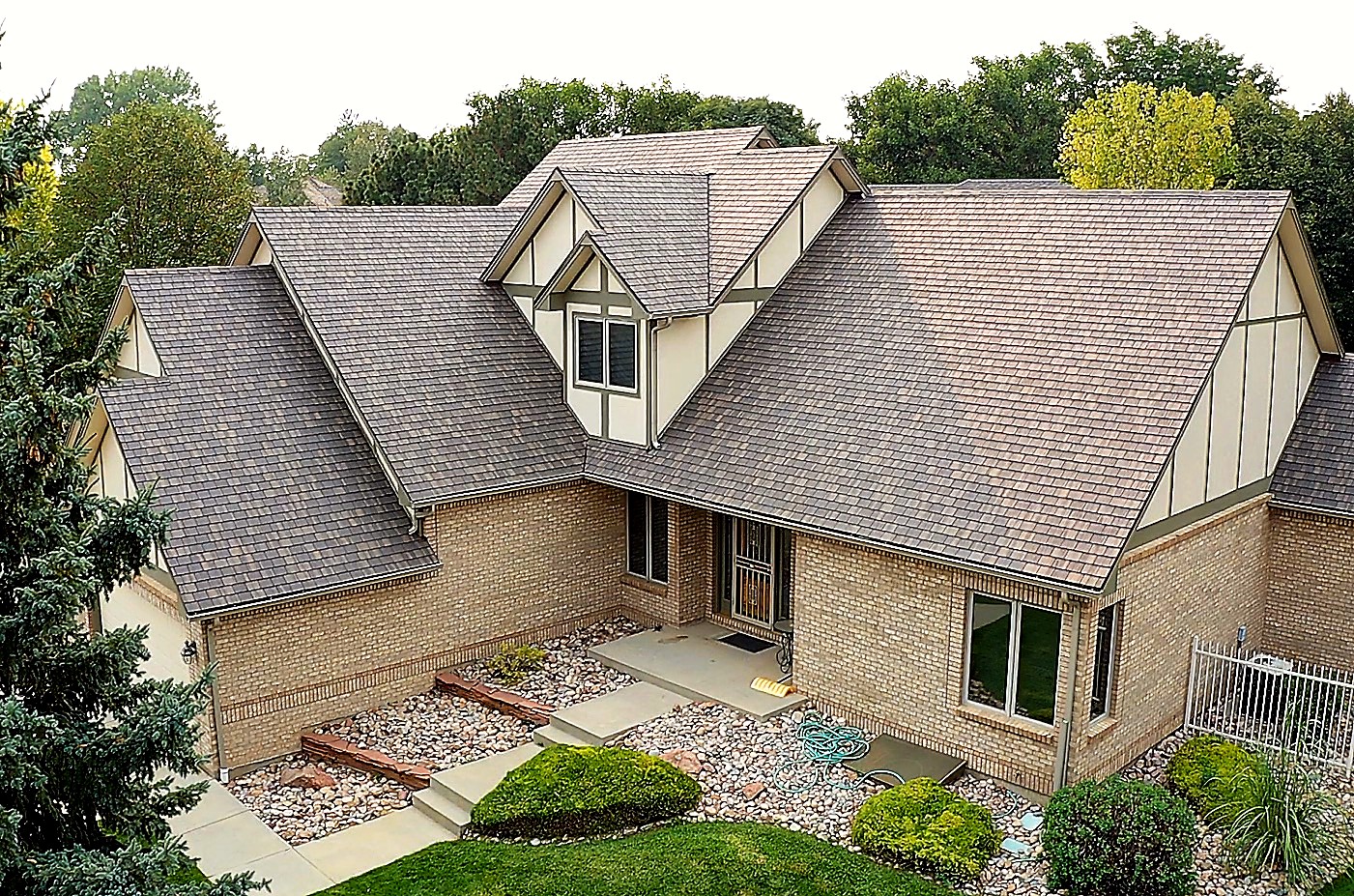 Aerial view of an F-Wave synthetic shake shingle roof replacement on a brick Tudor-style home in Longmont, Colorado, installed by Northern Lights Exteriors