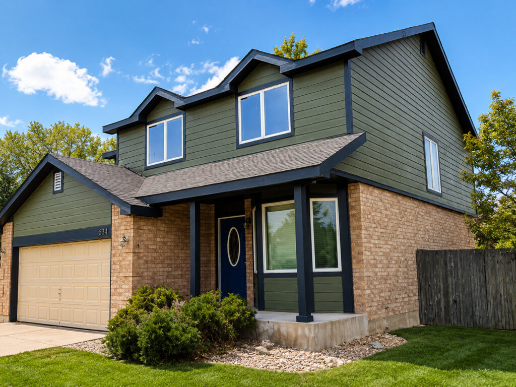 Completed James Hardie fiber cement siding replacement in Northglenn, CO featuring Mountain Sage Hardie lap siding, Iron Gray trim and existing brick installed by Northern Lights Exteriors.