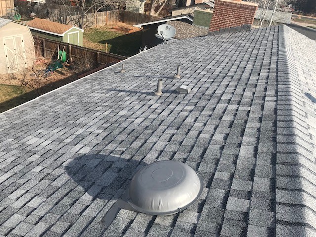 Newly installed architectural asphalt shingle roof on a Windsor, Colorado home, showing the dome attic vent, flashed plumbing vent stacks and ridge cap shingles along the ridge line.