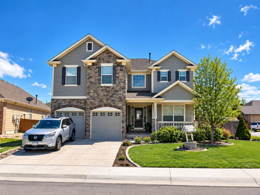 Two-story home in Thornton, CO with a new dark asphalt shingle roof installed by Northern Lights Exteriors, gray siding and stone accents